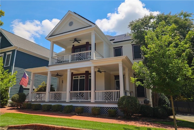 view of front facade with a ceiling fan, covered porch, a balcony, and roof mounted solar panels