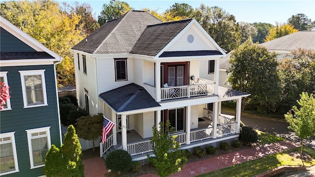 rear view of property with a porch, roof with shingles, and a balcony