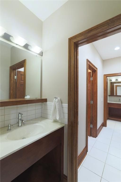 bathroom with tile patterned flooring, baseboards, decorative backsplash, and vanity