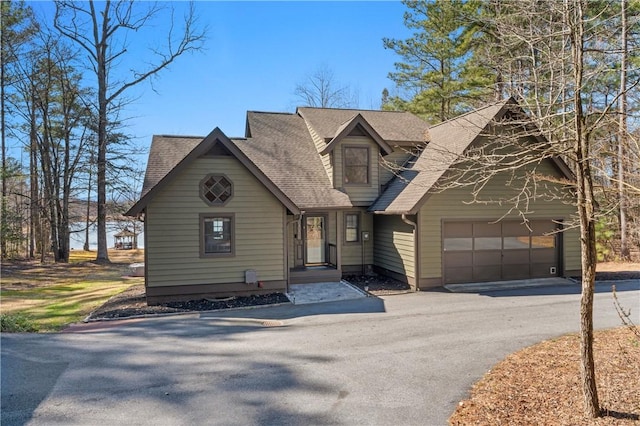 rustic home with a garage, a shingled roof, and aphalt driveway