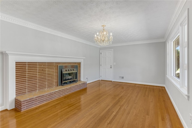 unfurnished living room featuring a textured ceiling, a fireplace, wood finished floors, and an inviting chandelier