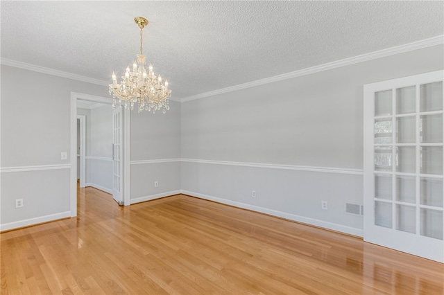 empty room featuring ornamental molding, a textured ceiling, baseboards, and wood finished floors