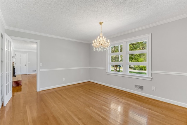 empty room featuring a notable chandelier, visible vents, baseboards, light wood-style floors, and ornamental molding