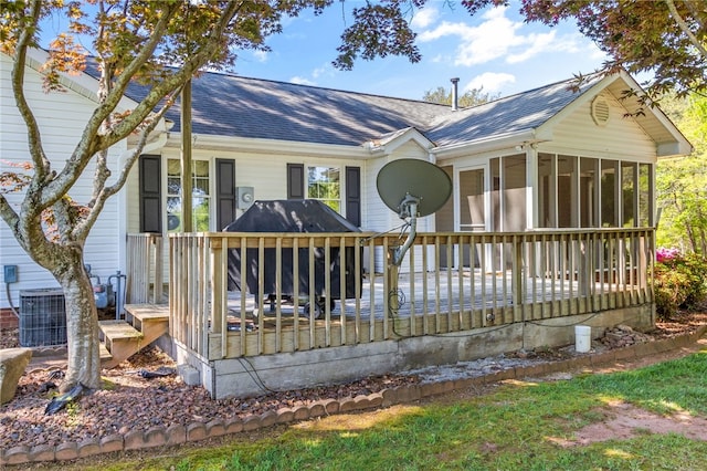 ranch-style home featuring central air condition unit, a sunroom, and a shingled roof