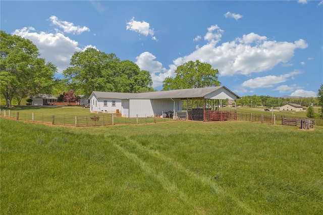 view of yard featuring fence, an outbuilding, an exterior structure, and a rural view