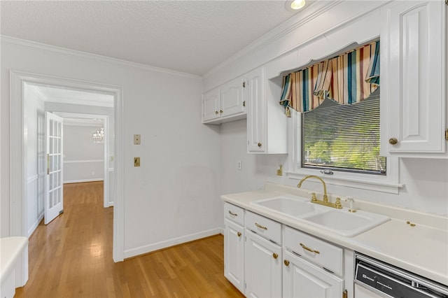 kitchen featuring white cabinets, light countertops, a sink, and dishwashing machine