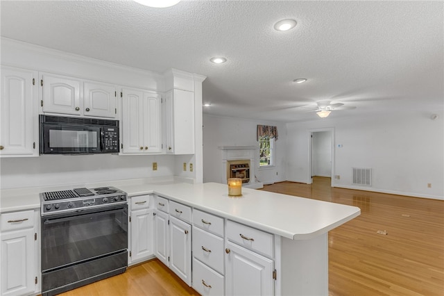 kitchen featuring black microwave, a peninsula, a fireplace, open floor plan, and range