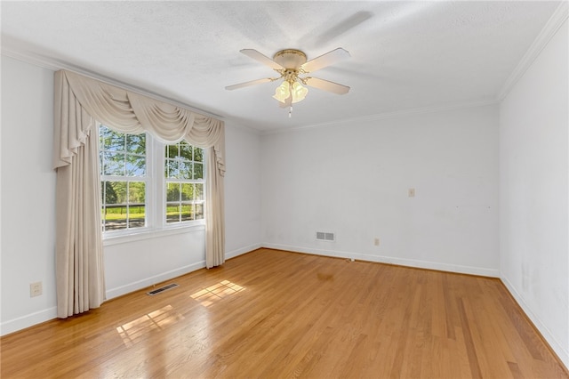 spare room with ornamental molding, light wood finished floors, visible vents, and baseboards