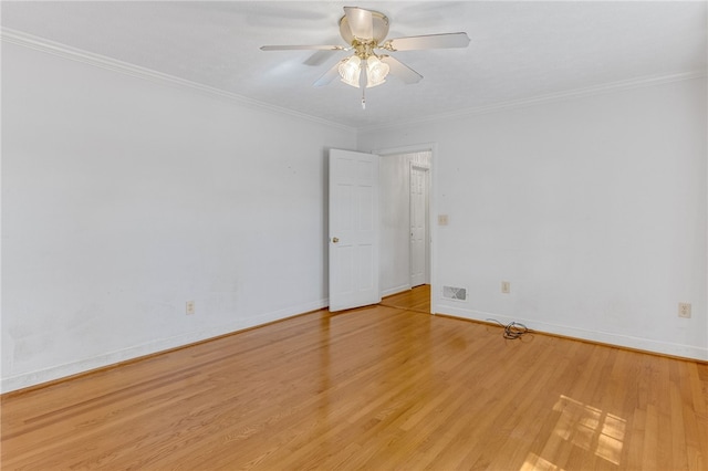 spare room featuring crown molding, visible vents, light wood-style flooring, a ceiling fan, and baseboards