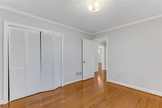 unfurnished bedroom with baseboards, a closet, visible vents, and wood finished floors