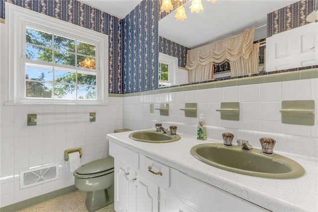 full bathroom featuring toilet, wallpapered walls, visible vents, and a sink