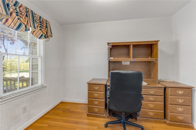 office space with light wood-style flooring, baseboards, and a textured ceiling