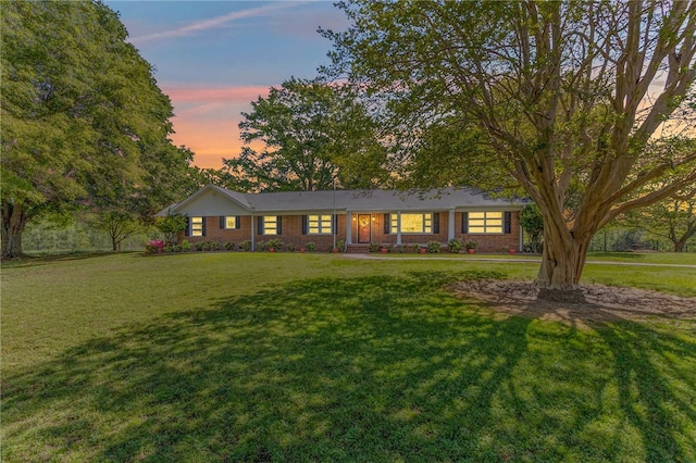 single story home featuring a yard and brick siding