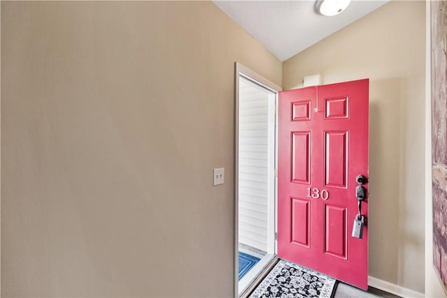 entryway featuring lofted ceiling and baseboards