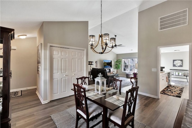 dining area featuring a chandelier, high vaulted ceiling, dark wood-style flooring, visible vents, and baseboards