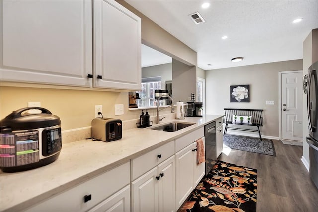 kitchen with visible vents, dishwasher, dark wood-style flooring, white cabinetry, and a sink