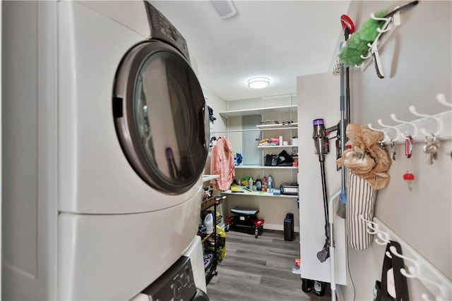 laundry room featuring laundry area, wood finished floors, and stacked washer and clothes dryer