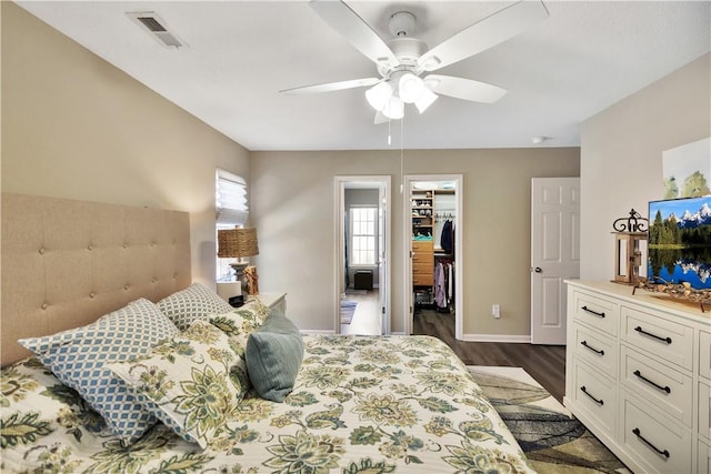 bedroom featuring dark wood-style flooring, a closet, visible vents, a spacious closet, and baseboards