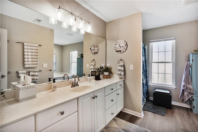 full bathroom with a wealth of natural light, visible vents, vanity, and wood finished floors