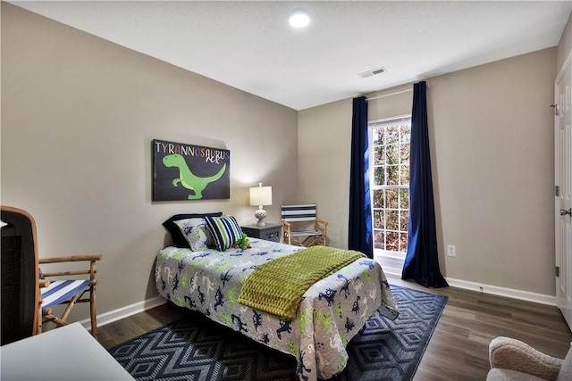 bedroom with wood finished floors, visible vents, and baseboards