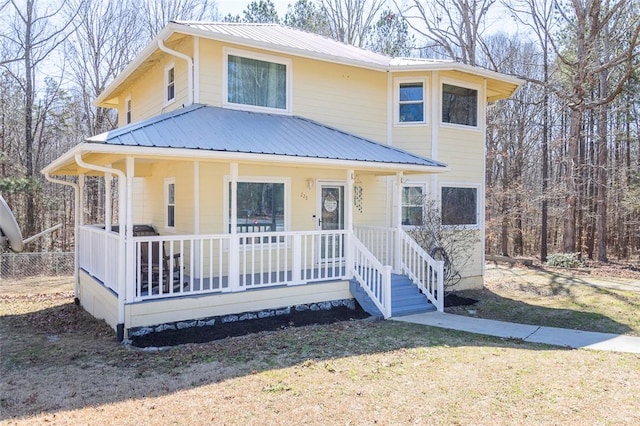 view of front of home with covered porch, fence, metal roof, and a front yard