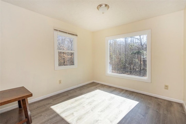 empty room with plenty of natural light, baseboards, and wood finished floors