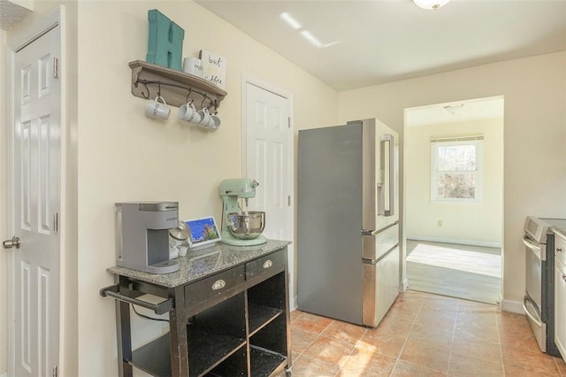 kitchen featuring light tile patterned floors, stainless steel appliances, open shelves, and baseboards