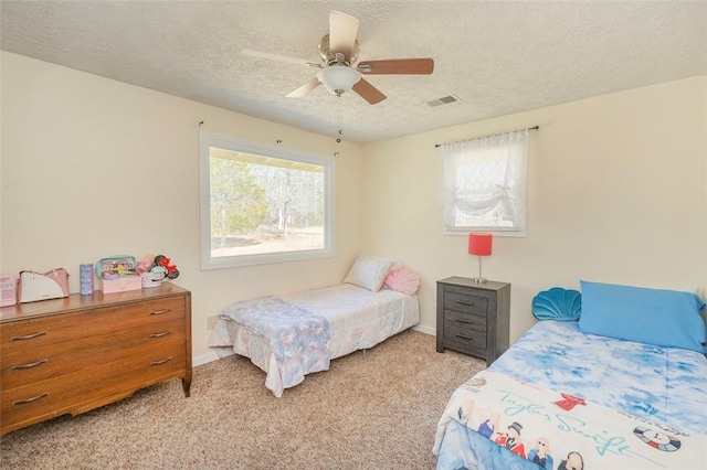 bedroom featuring ceiling fan, visible vents, a textured ceiling, and light colored carpet