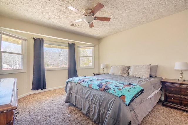 carpeted bedroom featuring baseboards, visible vents, ceiling fan, and a textured ceiling