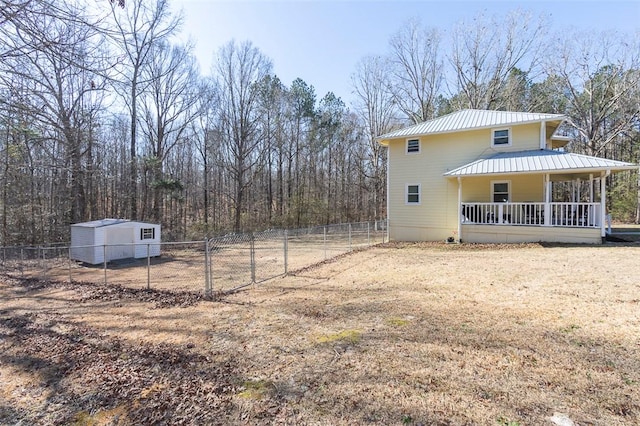 exterior space featuring covered porch, fence, metal roof, and an outdoor structure