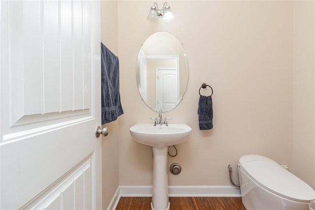 bathroom with a sink, toilet, baseboards, and wood finished floors