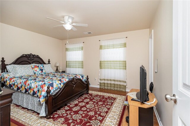 bedroom with visible vents, ceiling fan, baseboards, and wood finished floors