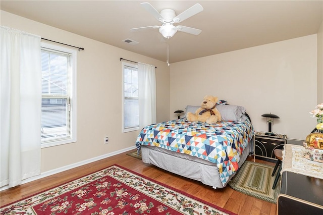 bedroom with visible vents, ceiling fan, baseboards, and wood finished floors