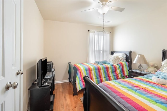 bedroom featuring baseboards, wood finished floors, visible vents, and a ceiling fan