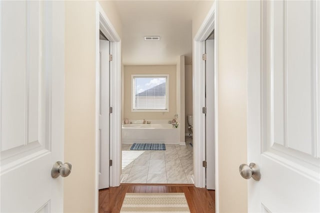 hall featuring visible vents and wood finished floors