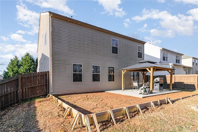 back of property with a fenced backyard, a patio, and a gazebo