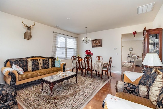 living area featuring baseboards, a notable chandelier, visible vents, and wood finished floors