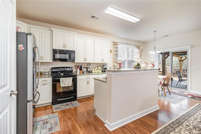 kitchen featuring pendant lighting, white cabinets, light wood-style flooring, and black appliances