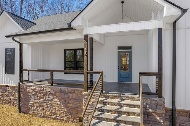 view of exterior entry with a porch and roof with shingles