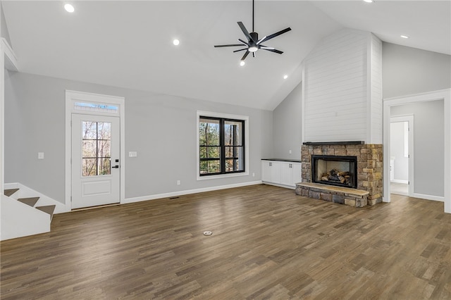 unfurnished living room with a healthy amount of sunlight, ceiling fan, wood finished floors, and a stone fireplace