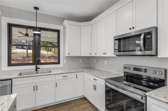 kitchen with decorative light fixtures, dark wood finished floors, stainless steel appliances, white cabinetry, and a sink