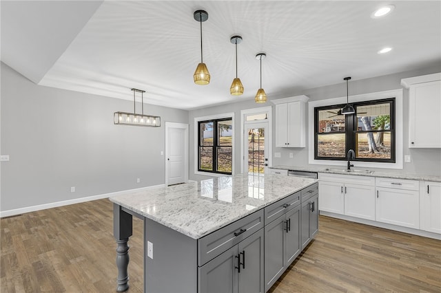 kitchen with a sink, wood finished floors, gray cabinets, and white cabinets