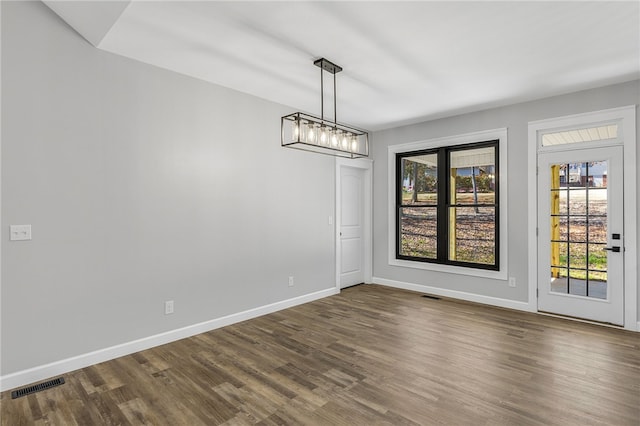 unfurnished dining area featuring dark wood-type flooring, a healthy amount of sunlight, visible vents, and baseboards