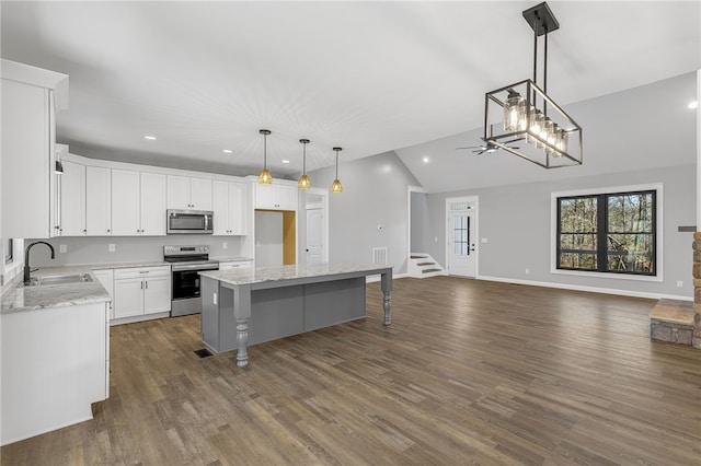 kitchen featuring stainless steel appliances, a sink, vaulted ceiling, open floor plan, and a center island