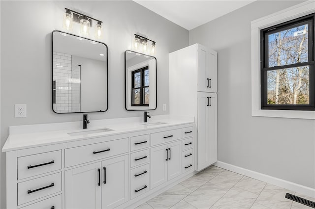 bathroom featuring marble finish floor, a sink, baseboards, and double vanity