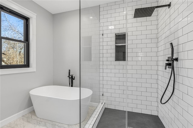 full bath featuring a freestanding tub, a tile shower, marble finish floor, and baseboards