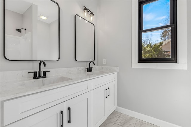 bathroom featuring marble finish floor, a sink, baseboards, and double vanity