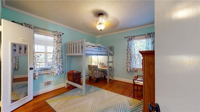 bedroom with visible vents, multiple windows, and wood finished floors