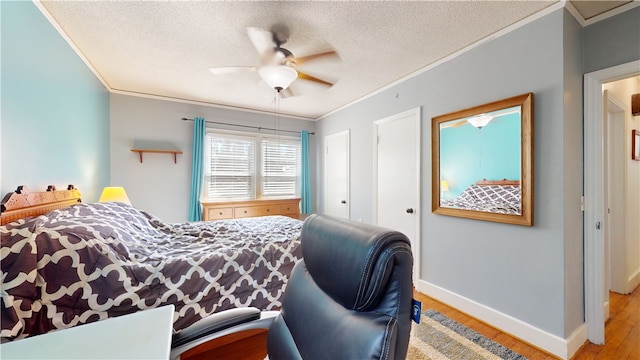 bedroom featuring a textured ceiling, baseboards, crown molding, and wood finished floors