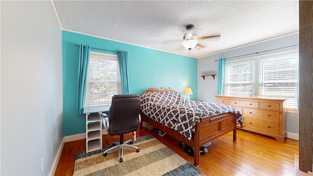 bedroom featuring a textured ceiling, crown molding, light wood-style flooring, and baseboards